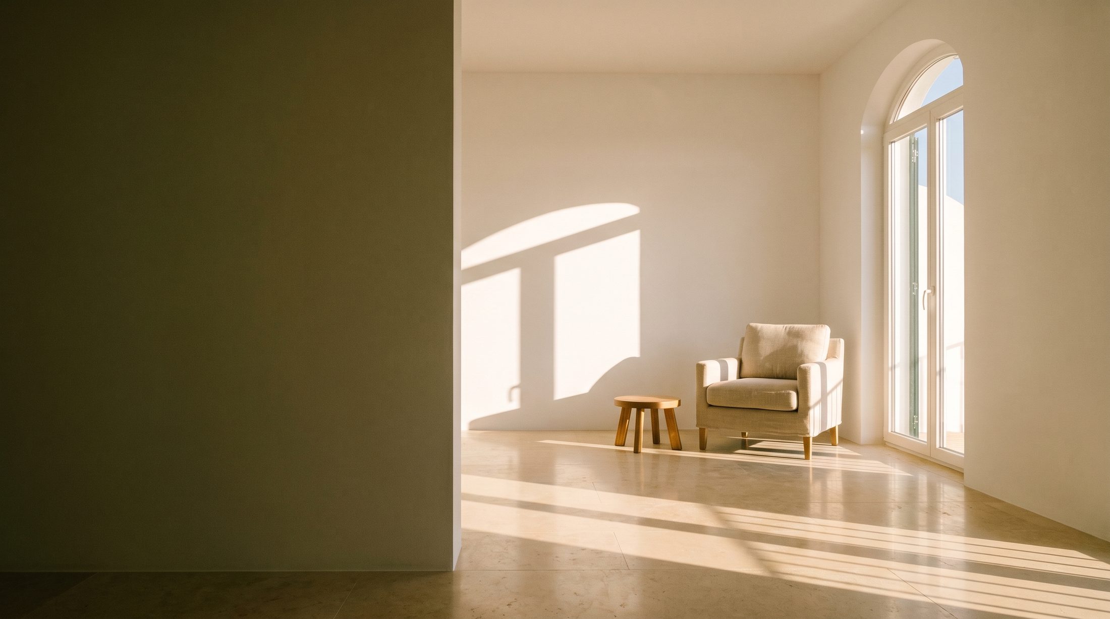 Sala acabada de renovar e de limpar: parede verde-escura à esquerda, luz de fim de tarde a entrar por uma janela em arco e o chão de pedra polida a refleti-la